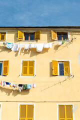 Laundry clotes hanging on wires on a residential building, with yellow windows. Blue sky on the...