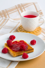 Cup of red tea and toasted bread with raspberry jam