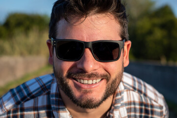 Retrato de hombre apuesto con gafas de sol mirando de cerca a cámara