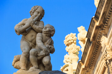 Fototapeta na wymiar Cityscape - view of a sculptures of a pair of cupids on the balustrade of the architecture Zwinger Palace complex in Dresden close-up, Germany