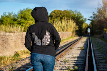 Mujer solitaria caminado por las vías del tren un día soleado al atardedcer.
