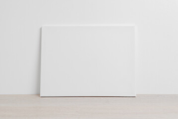 Art canvas in a horizontal position on the floor leaning against a white wall. Clean cloth for...