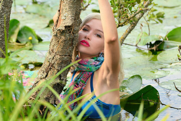 glamorous beautiful girl bathes in a lake with water lilies.