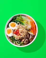 Ramen noodle soup with eggs, mushrooms, pak choi in hard light on orange
