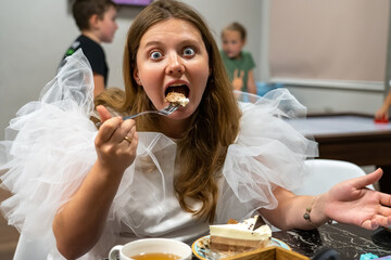 Portrait of nice cute woman staring at camera opens her mouth wide while eating sweet cake
