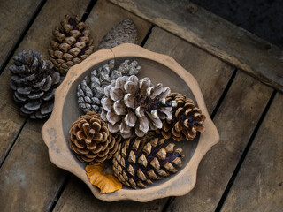 An old, pottery bowl full of pine cones on wooden box. Rustic.