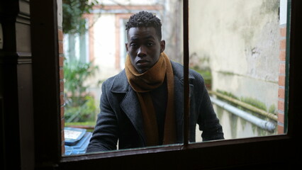 Hurried young black man leaving home opening front door