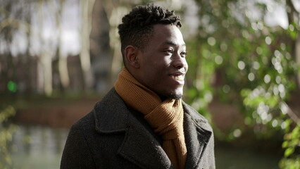 Happy black man walking in nature during winter season smiling and feeling carefree