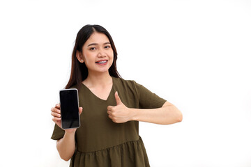 Fototapeta premium Happy young asian woman standing while showing blank screen of cell phone and thumbs up. Isolated on white