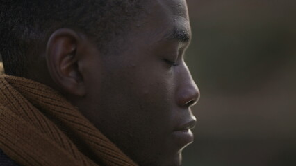 Meditative black man closing eyes in contemplation, close-up African person face