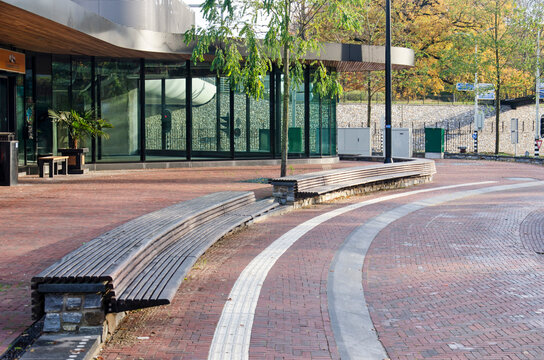 Driebergen, The Netherlands, November 18, 2022: gently curving road with wooden bench at the Kiss and Ride area in front of Driebergen-Zeist railway station