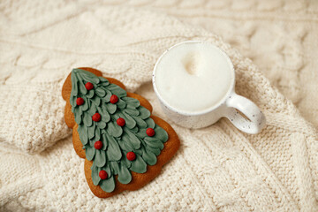 Warm cup of coffee and christmas tree gingerbread cookie on knitted sweater. Atmospheric winter hygge. Christmas banner. Cozy holidays