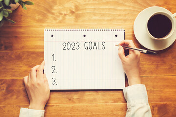 2023 goals with a person holding a pen on a wooden desk