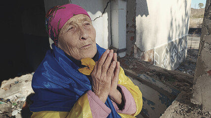 War in Ukraine. The old grandmother is tearfully praying. Grandmother prays for an end to the war....