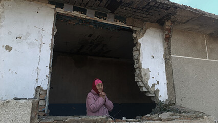 An old woman in tears because of the war. A grandmother in a destroyed house. An old grandmother...