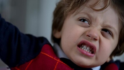 One angry young boy close up face. Portrait of an upset little kid. Unhappy child