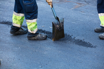 asphalt on the ground, road construction workers distribute the asphalt and paving