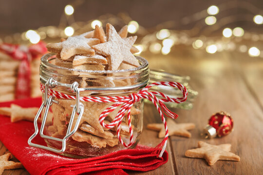 Christmas Shortbread Cookies Or Gingerbread Stars With Red Ribbon, Festive Decoration, Fir Tree,balls And Light Garland. Traditional German Cookies. Christmas Celebration Traditions Family Culinary.