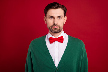 Portrait photo of confident elegant mister man wear green cardigan red bowtie nice haircut before christmas holiday isolated on red color background