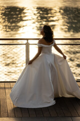 Fototapeta na wymiar Happy young bride woman in white dress running,, summer shooting near a water. Wedding rest, relax honeymoon concept.