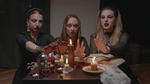 4K. Three female witches in a dark room conduct mystical sessions