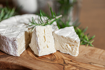 Delicious italian Camembert cheese. Fresh Camembert cheese with rosemary on a wooden cut board....