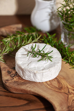 Delicious italian Camembert cheese. Fresh Camembert cheese with rosemary on a wooden cut board. Tasty cheese - Camembert