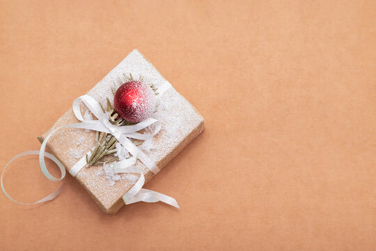 Christmas gift box with a white ribbon on a beige background. Christmas or New Year greeting card.