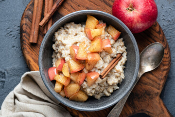 Oatmeal porridge with apple and cinnamon in bowl, top view. Healthy breakfast meal - obrazy, fototapety, plakaty