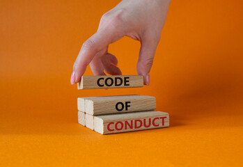 Code of conduct symbol. Wooden blocks with words Code of conduct. Beautiful orange background. Businessman hand. Business and Code of conduct concept. Copy space.