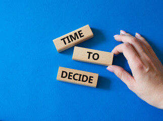 Time to decide symbol. Concept words Time to decide on wooden blocks. Beautiful blue background. Busimessman hand. Business and Time to decide concept. Copy space.