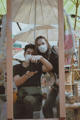 Young couple using camera shooting reflection photo from mirror in market when them travelling