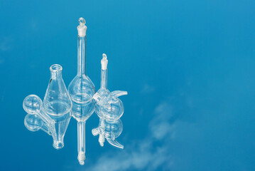 Various laboratory glassware on a mirror background with sky reflection