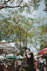 Young man traveller touring in street market and using his camera for take a photo