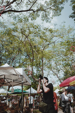 Young man traveller touring in street market and using his camera for take a photo