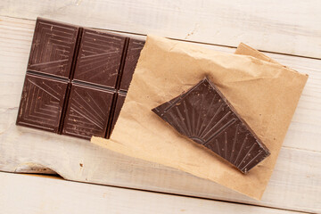 One bar of dark dark chocolate on a wooden table, macro, top view.