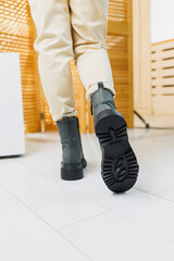 Fashionable women's stylish leather boots. Green women's genuine leather boots on feet close-up. New collection of winter shoes for stylish girls.