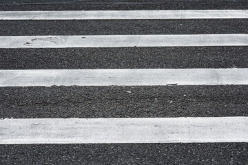 Full pedestrian crosswalk with white stripes painted on black asphalt