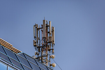 5G antenna on the roof of a building made of glass against clear sky