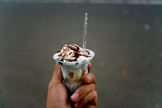 Hand holding indonesian traditional ice cream in plastic cup called es puter or es dong dong