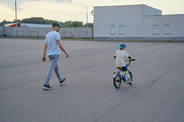 Father help his son ride a bicycle