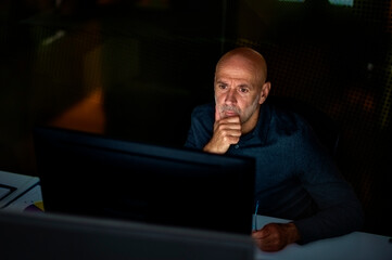 Businessman looking thoughtfully while working in late evening at the office