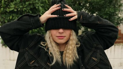 Girl in a black wool cap dancing and making faces in the street