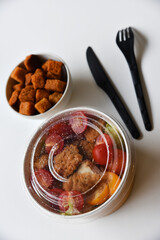 Caesar salad with tomatoes and breadcrumbs in containers. Delicious breakfast with accessories on a white background. Salad with meat and breadcrumbs.