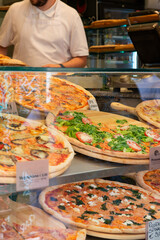Different types of pizza are sold in a street food cafe in Italy