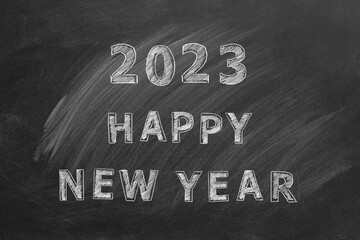 Hand drawn text 2023 HAPPY NEW YEAR on blackboard.