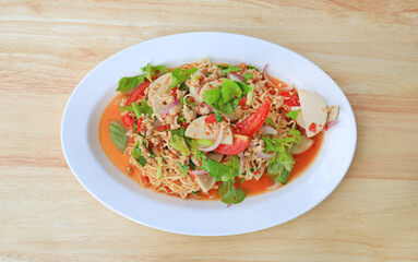 Spicy Instant Noodle Salad with Sliced Vietnamese Pork Sausage in white plate on wood background - Thai food. Top view.