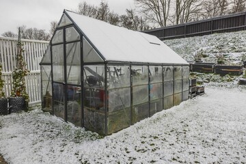 Beautiful winter view of garden plot in house with greenhouse and things put away for winter....