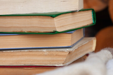 a close stack of old books on the woolen blanket  on wooden background in vintage style. Literature, education, hobby, reading and lifestyle