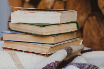 A stack of old books on the woolen blanket  on wooden background in vintage style. Literature,...